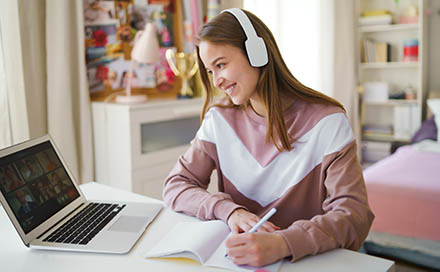 female using laptop, webcam and headsets