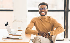 Man smiling siting at a desk with a computer