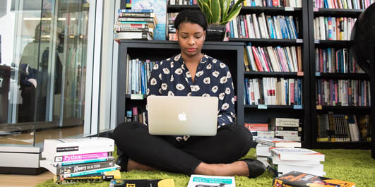 Student sitting on floor with books and notebook